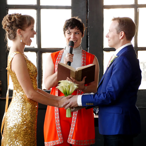 Happy wedding couple with smiling officiant