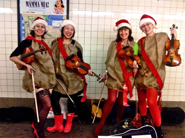 Women playing the violin dressed like Santa