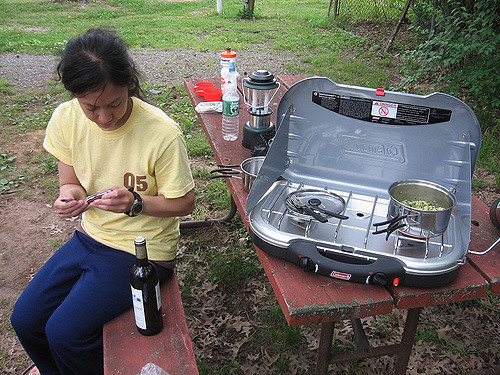 Woman opening bottle of wine while camping